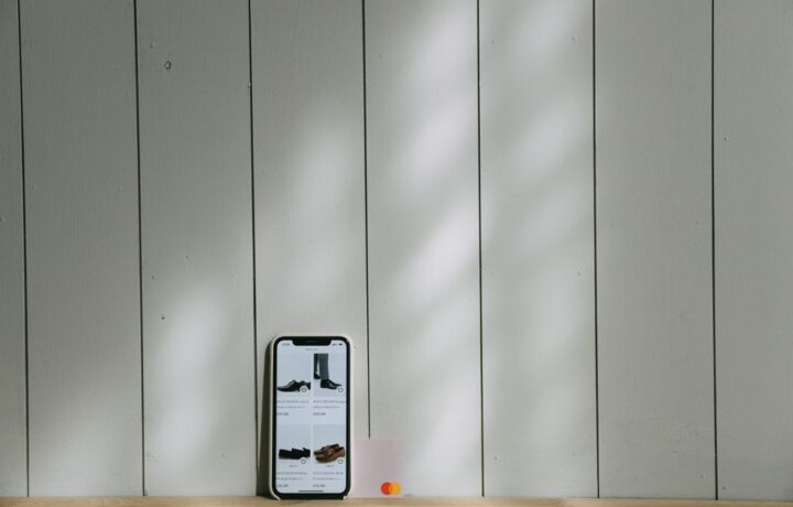 A smartphone and credit card sit on a wooden surface with soft lighting shadows.
