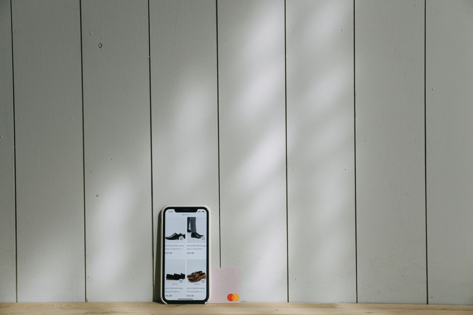 A smartphone and credit card sit on a wooden surface with soft lighting shadows.