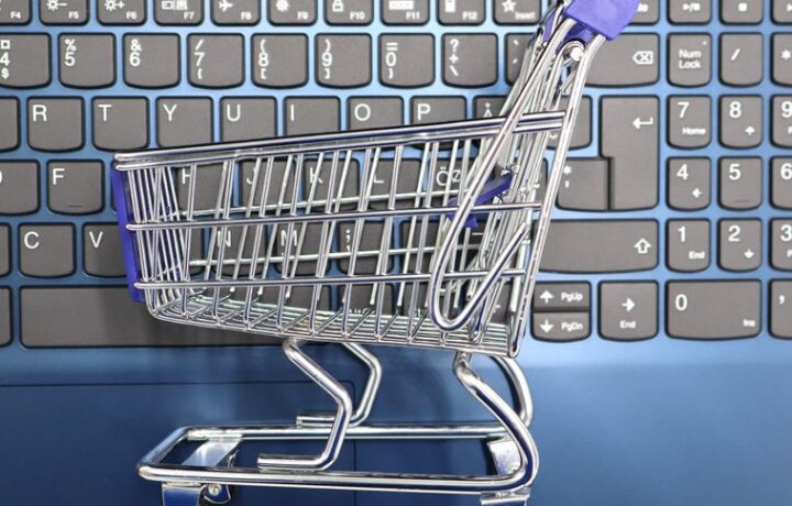 A miniature shopping cart placed on a laptop keyboard symbolizing online shopping and e-commerce.