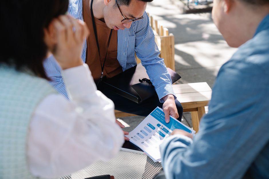 Group of professionals engaged in an outdoor business meeting discussing documents.