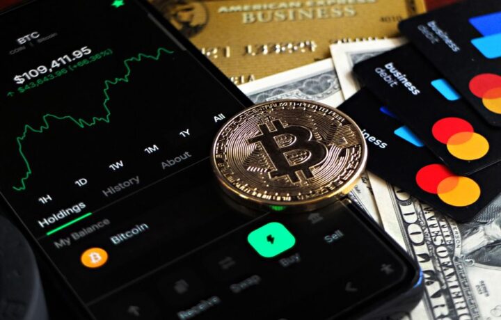 Bitcoin coin with financial data, credit cards, and currency on a desk.