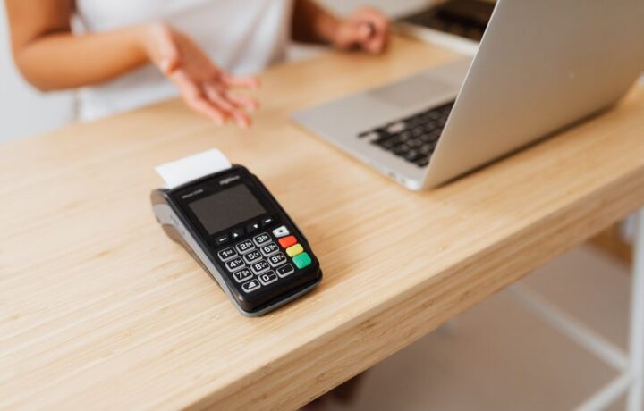 Close-up of a card reader on a wooden desk ready for contactless payment.