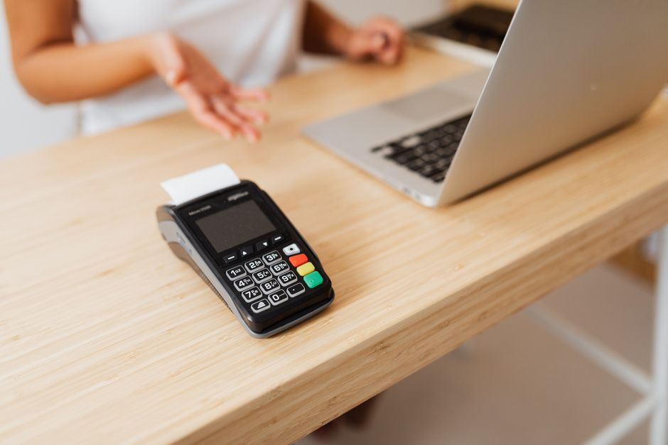 Close-up of a card reader on a wooden desk ready for contactless payment.
