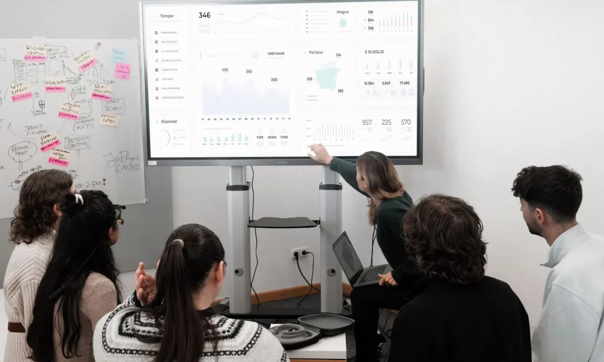 Profissionais discutindo KPIs essenciais para e-commerce com IA durante apresentação em tela grande
