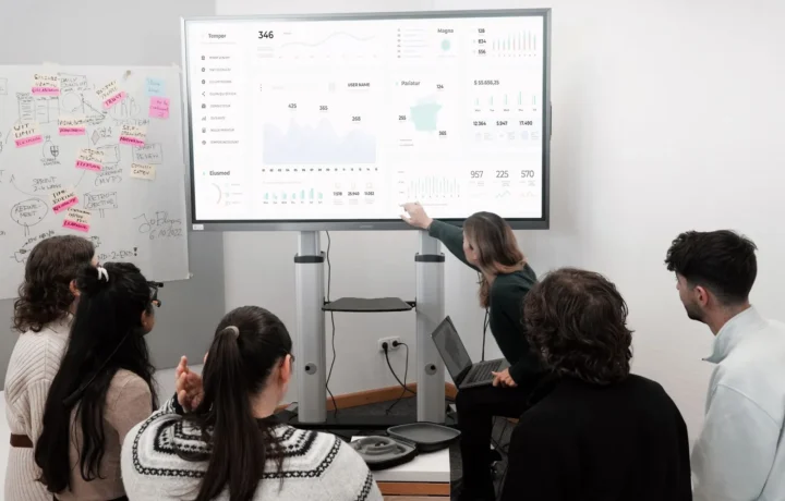 Profissionais discutindo KPIs essenciais para e-commerce com IA durante apresentação em tela grande