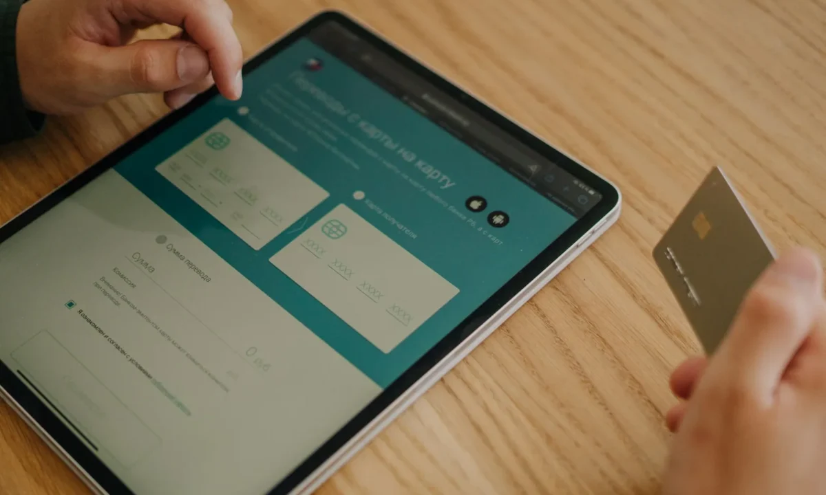 Mãos realizando uma compra online com tablet e cartão de crédito em uma mesa de madeira, representando ia link de pagamento