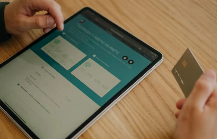 Mãos realizando uma compra online com tablet e cartão de crédito em uma mesa de madeira, representando ia link de pagamento